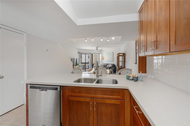 kitchen featuring backsplash, sink, stainless steel dishwasher, light tile patterned floors, and kitchen peninsula