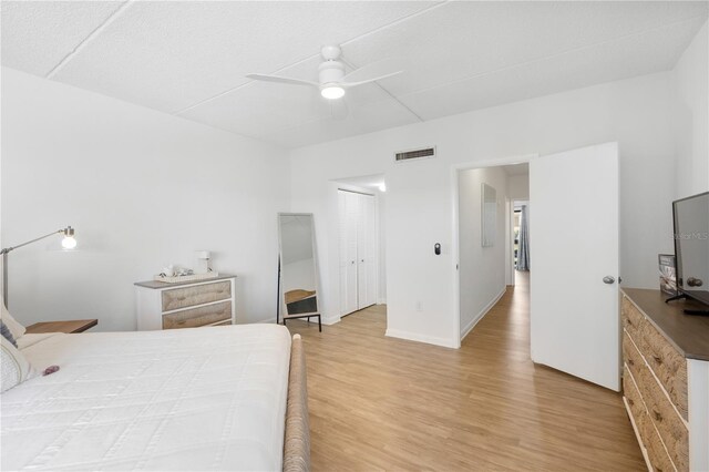 bedroom with ceiling fan, light hardwood / wood-style floors, and a closet