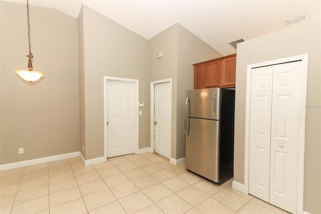 kitchen with high vaulted ceiling, stainless steel refrigerator, light tile floors, and pendant lighting