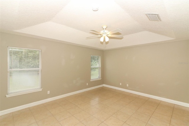 unfurnished room featuring a textured ceiling, ceiling fan, a tray ceiling, and light tile floors