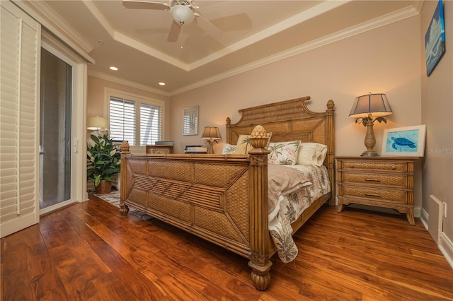 bedroom with hardwood / wood-style floors, ceiling fan, ornamental molding, and a tray ceiling