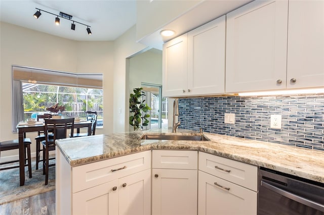 kitchen with light stone counters, sink, white cabinetry, light hardwood / wood-style flooring, and stainless steel dishwasher