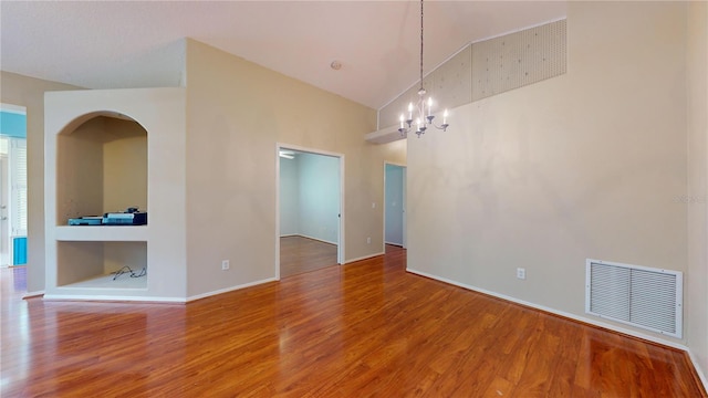 unfurnished room with hardwood / wood-style floors, high vaulted ceiling, and an inviting chandelier