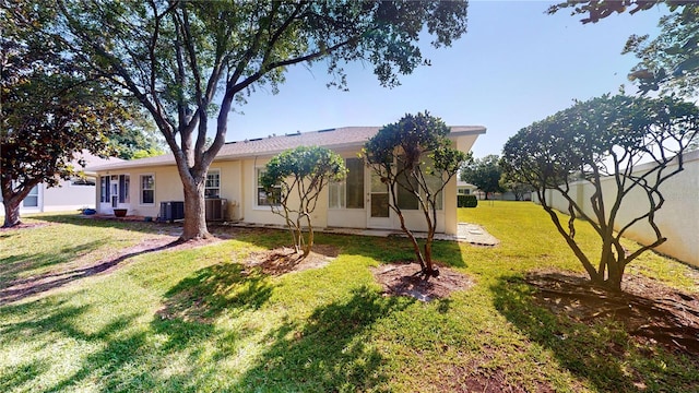 rear view of house with a yard and central AC