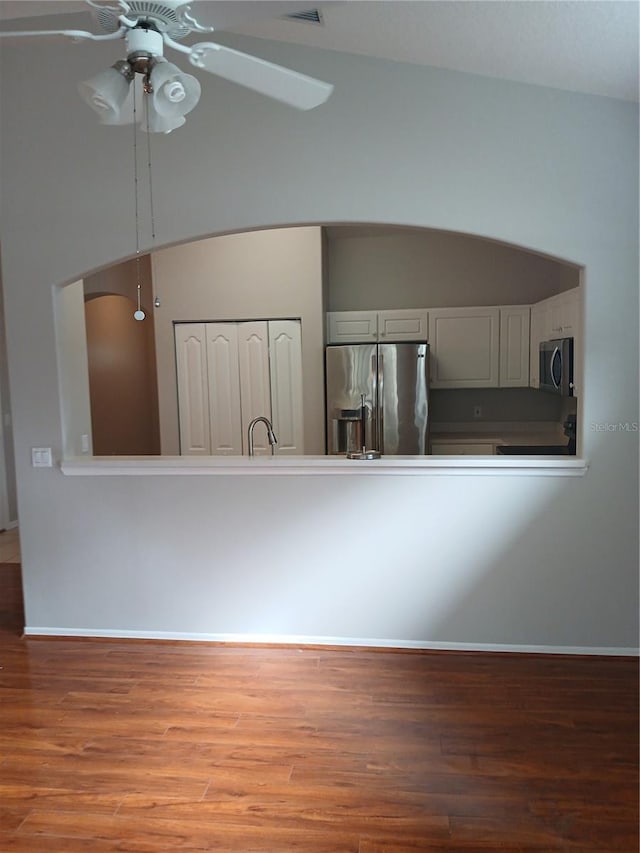 kitchen with ceiling fan, hardwood / wood-style floors, stainless steel appliances, and lofted ceiling