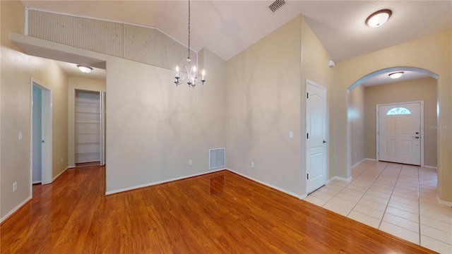 interior space with a textured ceiling, an inviting chandelier, high vaulted ceiling, and light hardwood / wood-style flooring