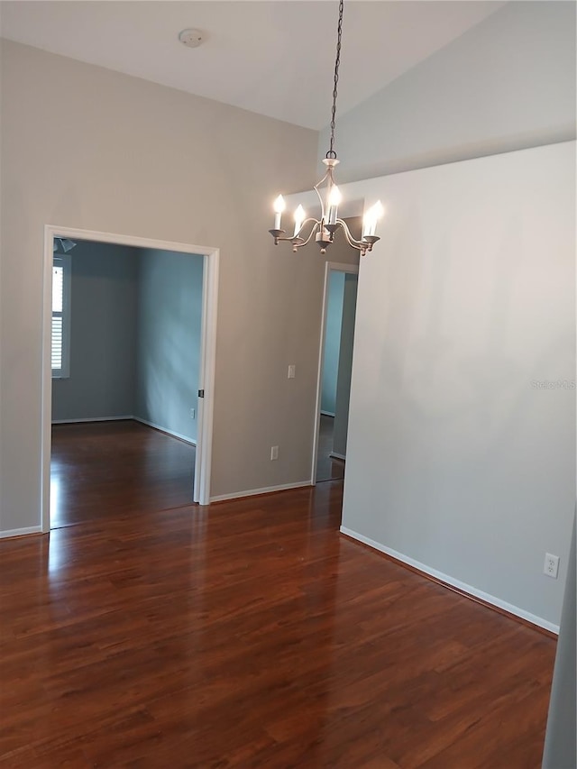 empty room featuring vaulted ceiling, dark hardwood / wood-style floors, and a notable chandelier