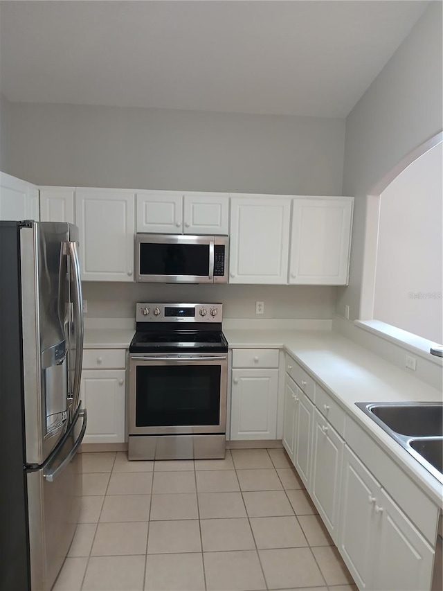 kitchen with light tile patterned floors, white cabinetry, and appliances with stainless steel finishes