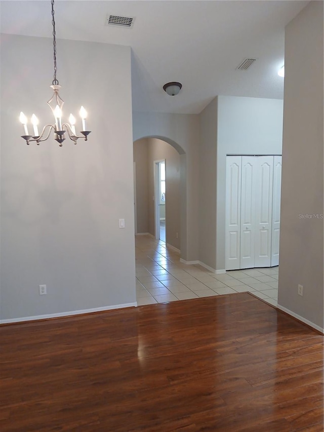 unfurnished room with light hardwood / wood-style flooring, a chandelier, and lofted ceiling