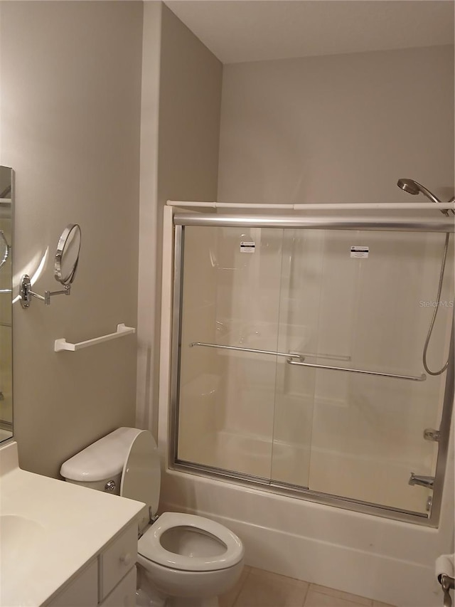 full bathroom featuring tile patterned floors, vanity, bath / shower combo with glass door, and toilet