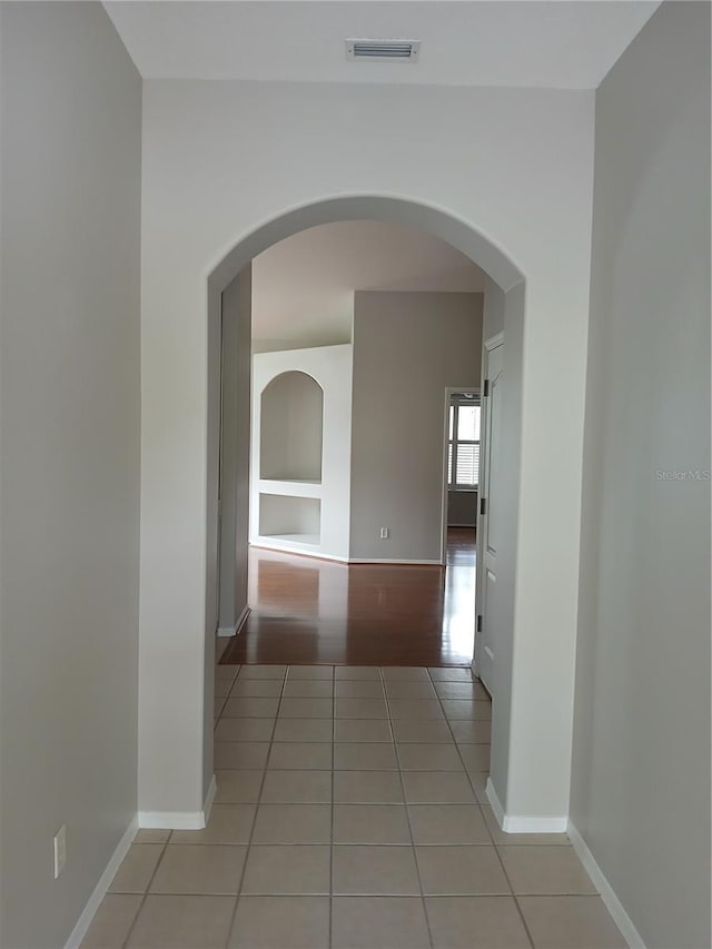 corridor with built in shelves and light tile patterned floors