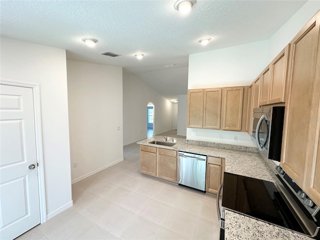 kitchen with sink, appliances with stainless steel finishes, light tile floors, and a textured ceiling