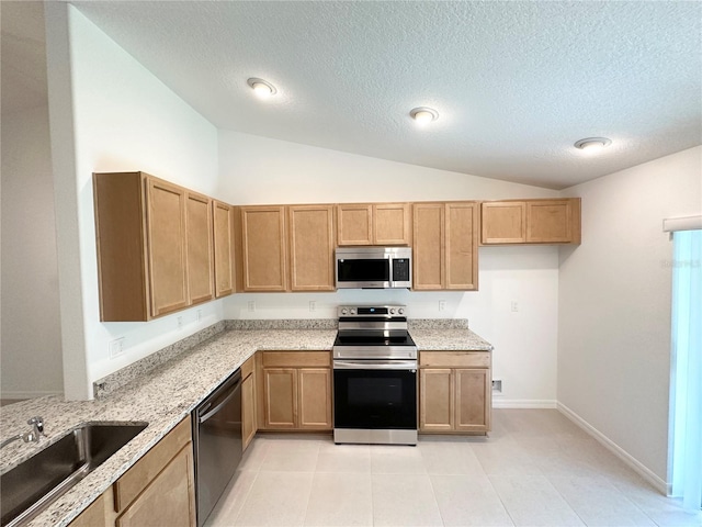 kitchen featuring stainless steel appliances, sink, light tile floors, vaulted ceiling, and a textured ceiling