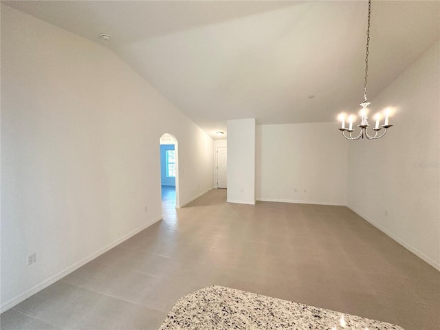 tiled empty room with lofted ceiling and a chandelier