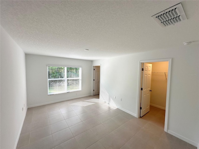 tiled empty room featuring a textured ceiling