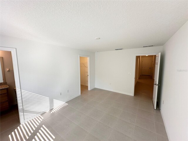 spare room with a textured ceiling and light tile flooring