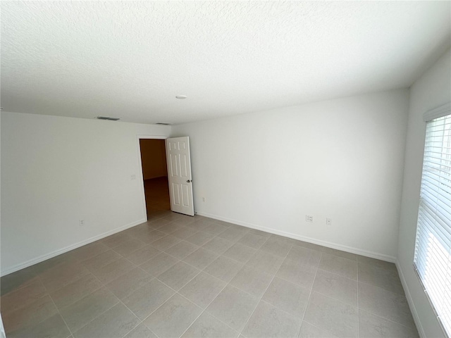 tiled spare room featuring plenty of natural light and a textured ceiling