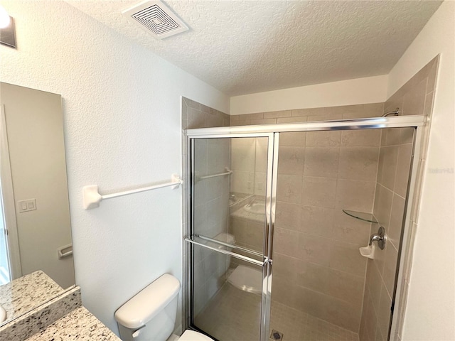 bathroom featuring walk in shower, a textured ceiling, vanity, and toilet