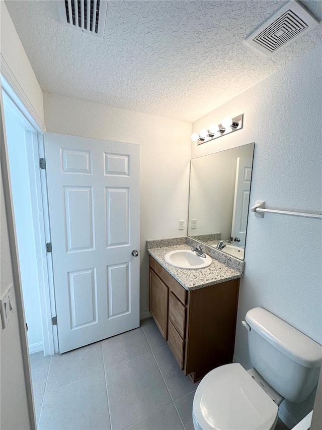 bathroom featuring a textured ceiling, vanity, toilet, and tile flooring