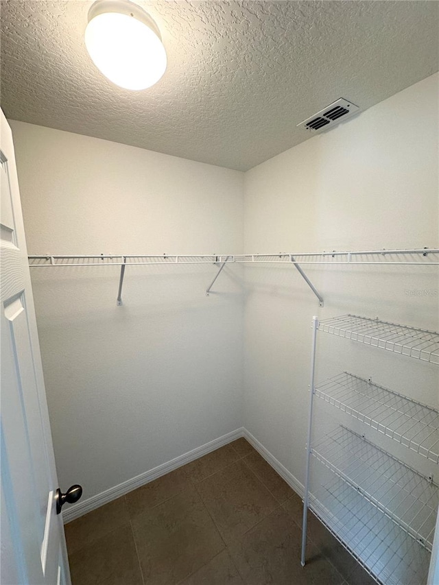 walk in closet with dark tile floors