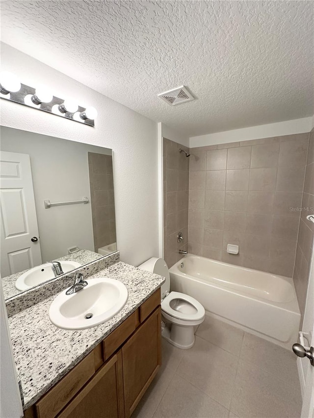 full bathroom featuring tiled shower / bath combo, oversized vanity, tile flooring, toilet, and a textured ceiling