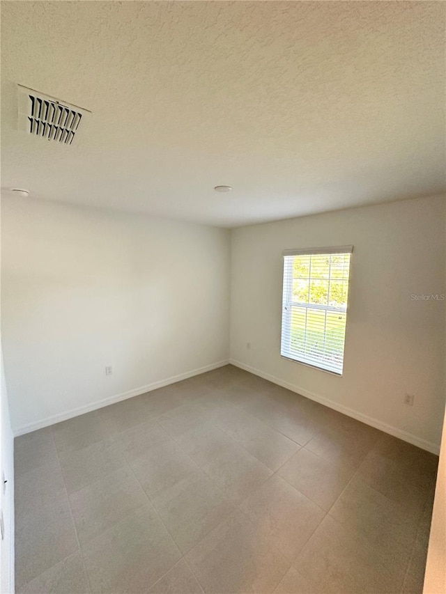 tiled spare room featuring a textured ceiling