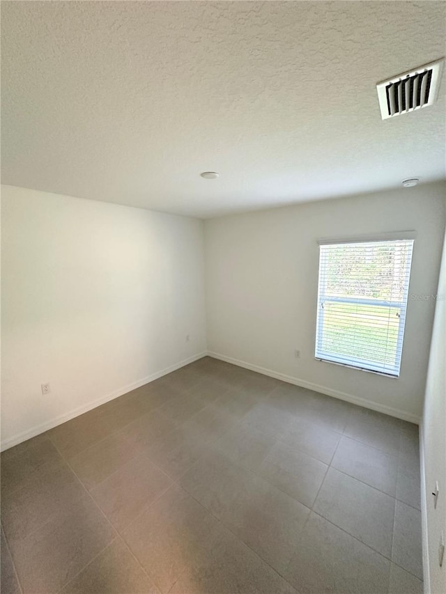 tiled spare room with a textured ceiling