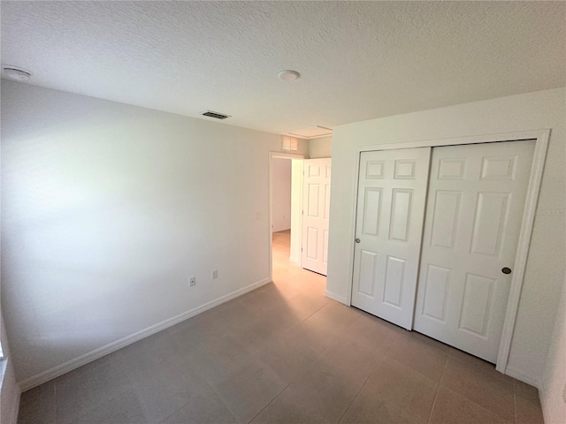 unfurnished bedroom featuring a closet, a textured ceiling, and tile floors