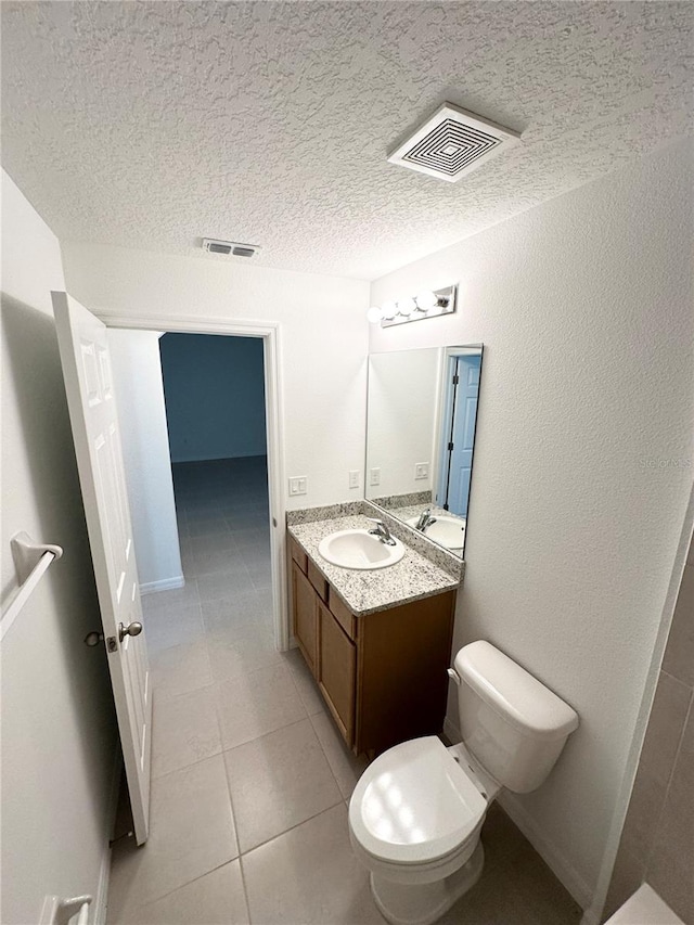 bathroom with vanity with extensive cabinet space, toilet, tile floors, and a textured ceiling