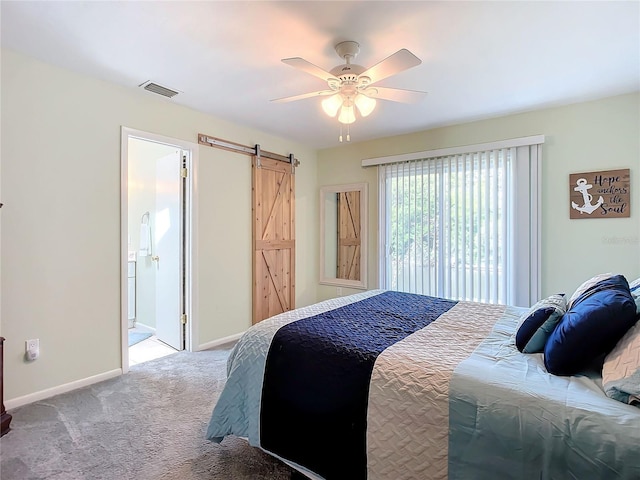 bedroom with ceiling fan, connected bathroom, a barn door, and light carpet