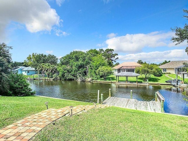 dock area with a gazebo, a water view, and a yard