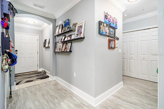 foyer entrance with light wood-type flooring and crown molding