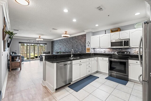 kitchen with sink, crown molding, white cabinetry, kitchen peninsula, and stainless steel appliances