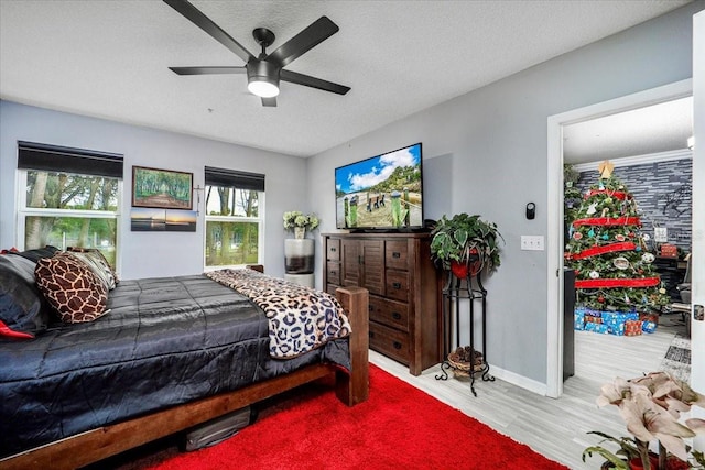 bedroom featuring multiple windows, ceiling fan, a textured ceiling, and hardwood / wood-style flooring