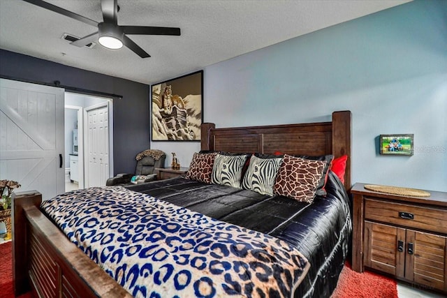 bedroom with carpet flooring, a textured ceiling, a barn door, and ceiling fan