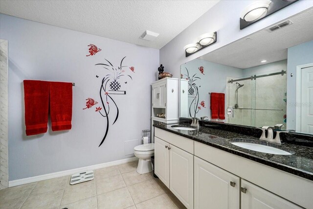 bathroom featuring an enclosed shower, vanity, a textured ceiling, tile patterned flooring, and toilet