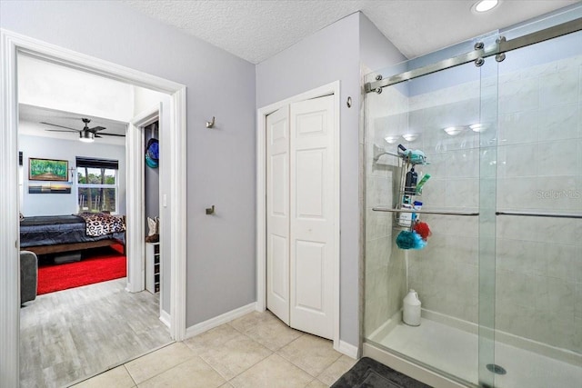 bathroom featuring a textured ceiling, ceiling fan, tile patterned flooring, and an enclosed shower