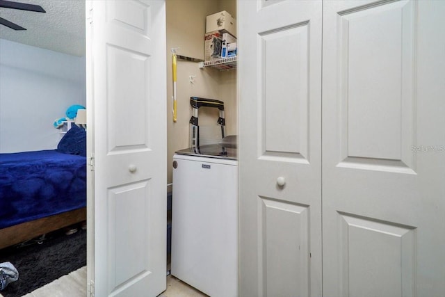 laundry room with ceiling fan and a textured ceiling