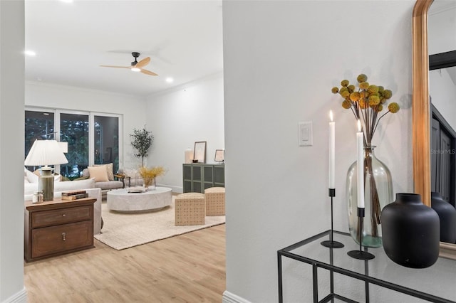 living room featuring light wood-type flooring, ceiling fan, and crown molding