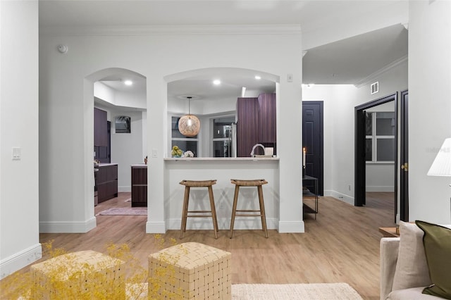 kitchen with crown molding, pendant lighting, and light hardwood / wood-style flooring