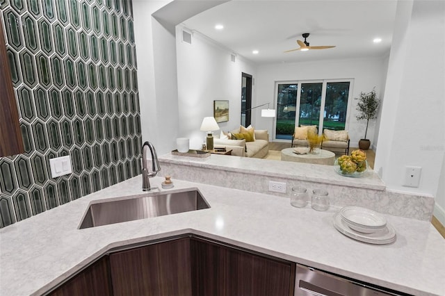 kitchen featuring stainless steel dishwasher, ceiling fan, light stone counters, and sink