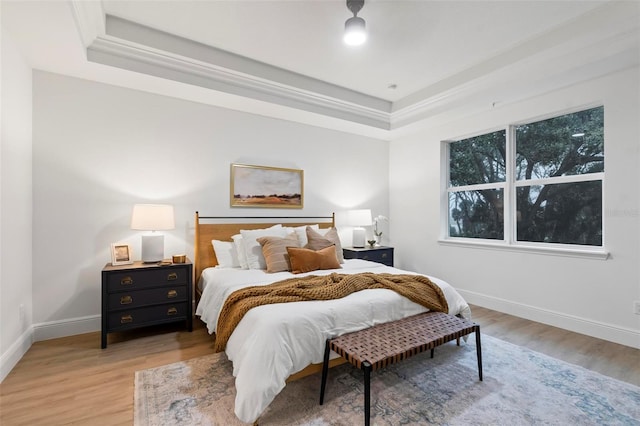 bedroom with light hardwood / wood-style flooring and a raised ceiling