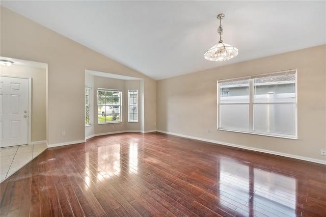 unfurnished room featuring hardwood / wood-style floors, vaulted ceiling, and an inviting chandelier