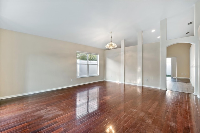 empty room with a chandelier and dark hardwood / wood-style flooring