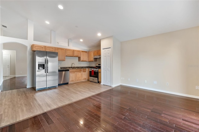 kitchen featuring high vaulted ceiling, sink, light brown cabinetry, hardwood / wood-style floors, and stainless steel appliances