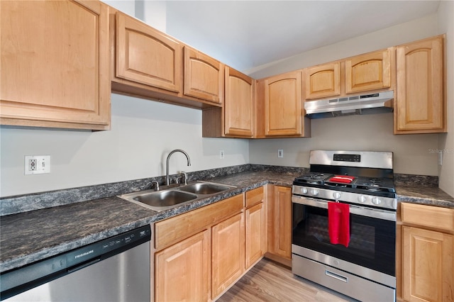 kitchen featuring appliances with stainless steel finishes, light hardwood / wood-style flooring, dark stone countertops, light brown cabinetry, and sink