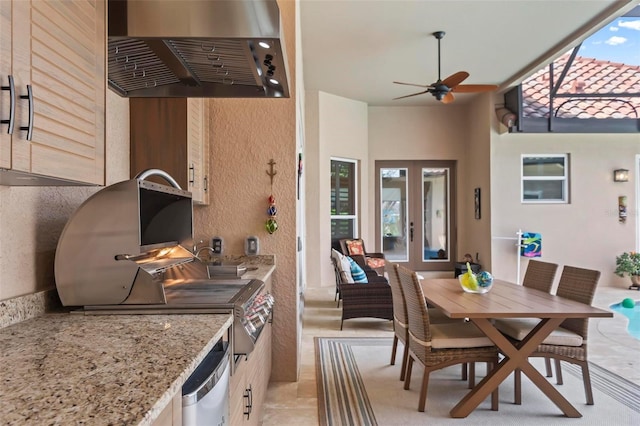 kitchen featuring ceiling fan, range hood, light stone counters, stainless steel dishwasher, and french doors