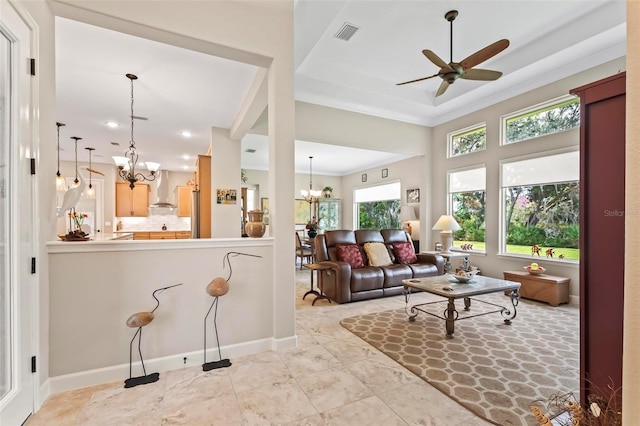 living room with a tray ceiling, ceiling fan with notable chandelier, and ornamental molding