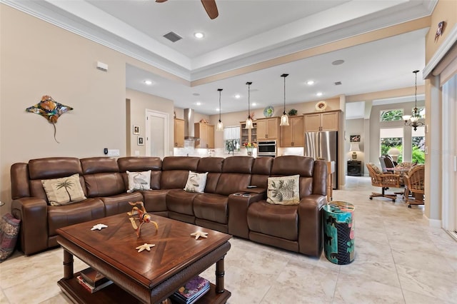 living room with crown molding, a raised ceiling, and ceiling fan with notable chandelier