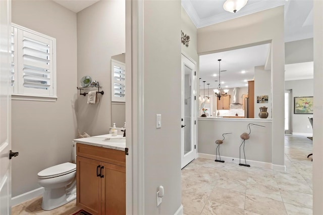 bathroom featuring ornamental molding, toilet, vanity, and a notable chandelier